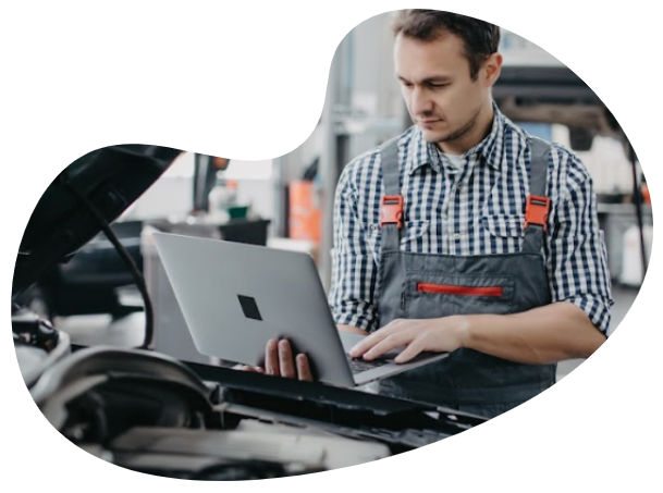 a man working on a laptop in front of a car