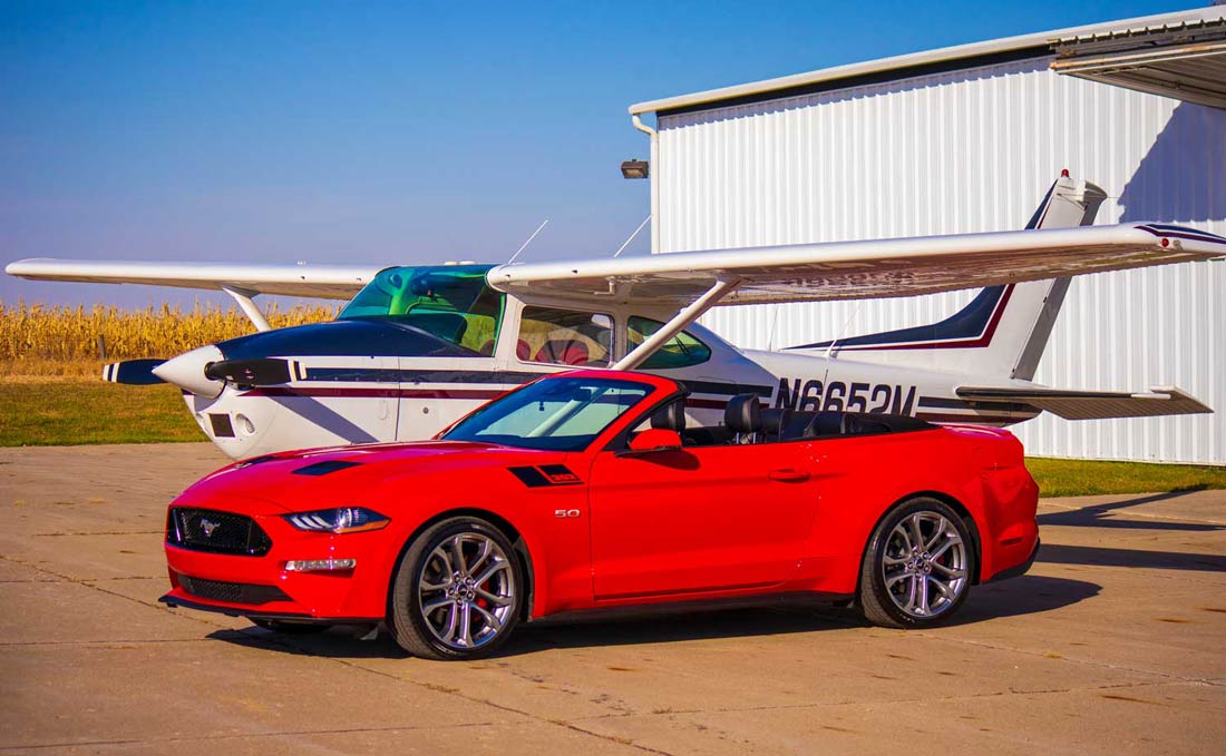 a white airplane and a red sports car