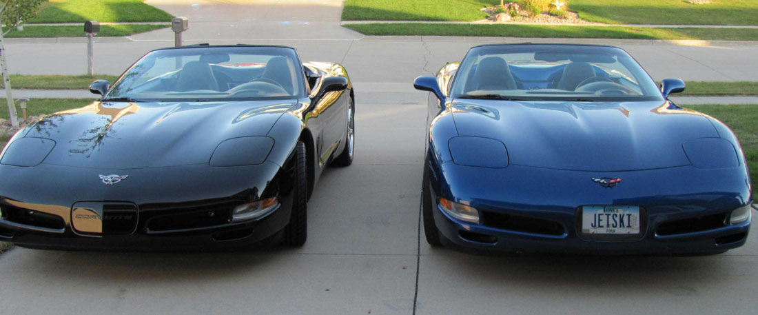 two blue and black sports cars parked in a driveway