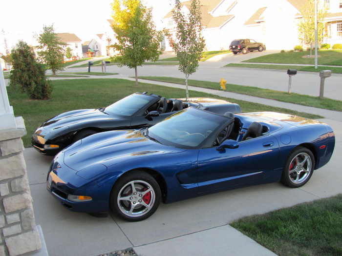 two blue and black sports cars parked in a driveway