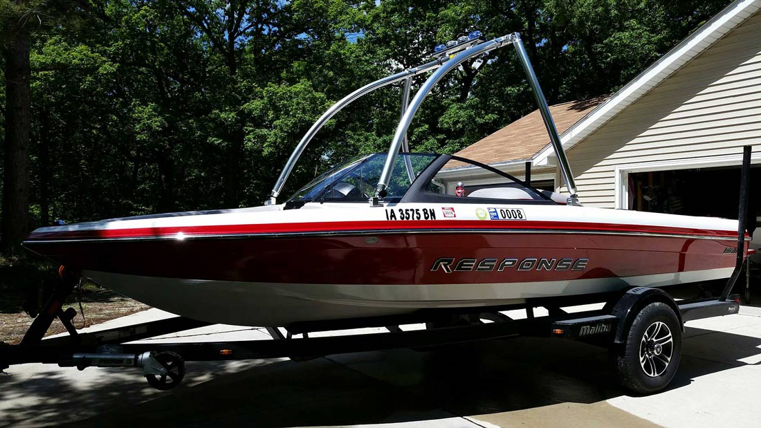 a red and white speed boat parked outside the garage