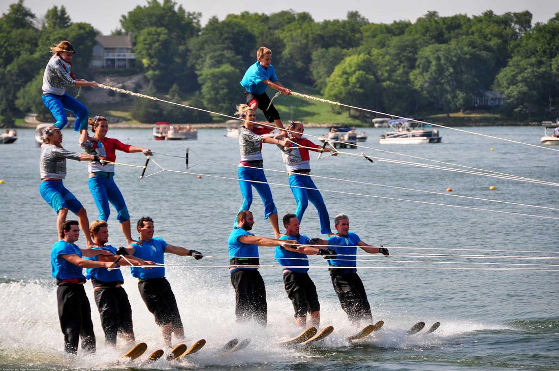a group of people performing while riding water skis on top of a lake