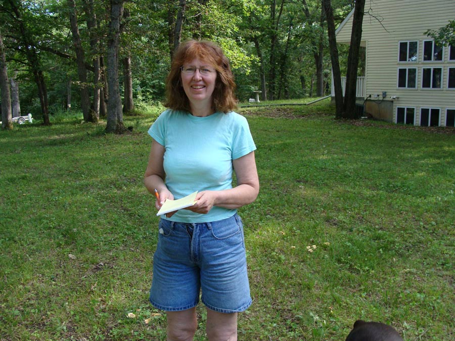 a woman standing in a yard holding a paper