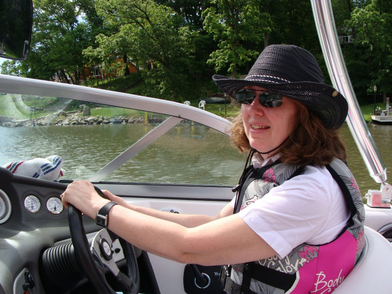 a woman driving a boat on a lake