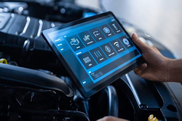 a person holding a tablet in front of a car engine